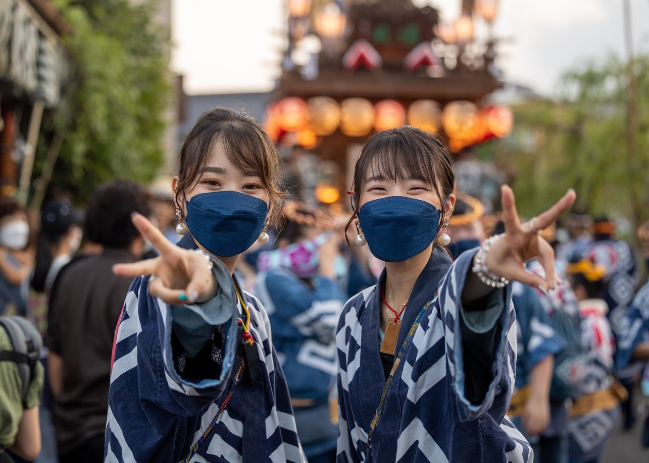 Young woman in traditional Japanese matsuri clothing looking at camera and making a peace sign in Matsuri